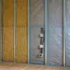 Intérieur d’un salon en rénovation, paroi ouverte montrant mur maçonné, isolant en laine minérale, membrane hygrovariable soigneusement scotchée, ossature métallique et prises avec manchons