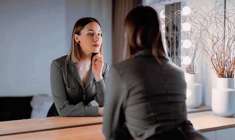 Femme regardant son reflet dans le miroir à l'intérieur d'une belle décoration intérieure.