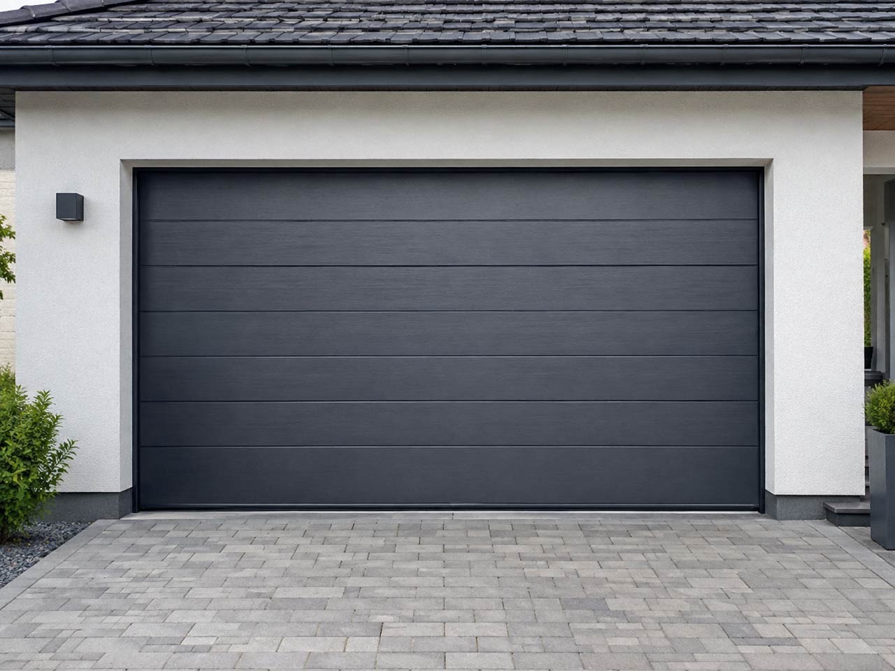 Porte de garage moderne anthracite à panneaux horizontaux sur une façade claire