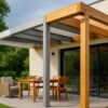Auvent contemporain au-dessus d’une terrasse familiale, mixant trois sections comparatives : une structure aluminium thermolaqué aux lignes nettes, une ossature acier galvanisé au rendu métallique mat, et un auvent bois Douglas au veinage visible ; lumière douce de fin d’après-midi, jardin verdoyant, façade claire