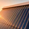 Capteur solaire thermique en gros plan sous soleil bas, reflets chauds et gouttes d’eau,