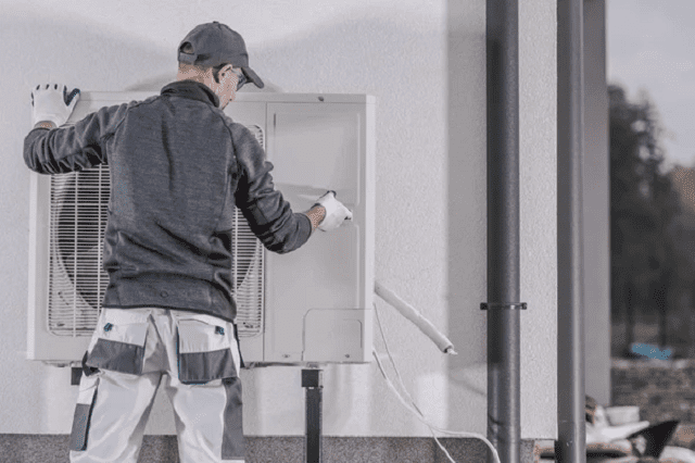 un homme installe une pompe à chaleur